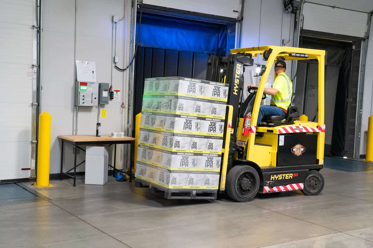 services-03 A warehouse employee operating a forklift to move stocked goods indoors. Perfect for industry and logistics visuals.